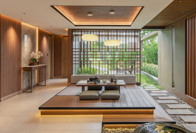 A warm, Japanese-inspired interior with a low wooden dining table, floor cushions, soft ambient lighting, and slatted wood partitions enhancing the serene atmosphere.