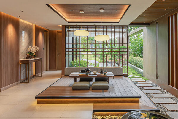 A warm, Japanese-inspired interior with a low wooden dining table, floor cushions, soft ambient lighting, and slatted wood partitions enhancing the serene atmosphere.